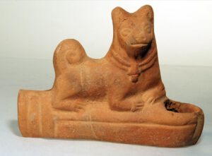 Terrakottalampe mit liegendem Hund, der ein zweireihiges Halsband mit Glocke trägt, Ägypten, 2. – 3. Jh. n. Chr., Martin-von-Wagner-Museum der Universität Würzburg. © Peter Neckermann, aus: Autengruber-Thüry, Heidelinde, Hunde in der römischen Antike. Rassen-Typen-Zucht-Haltung und Verwendung, Archäopress 2021