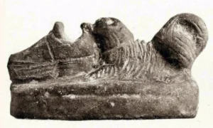 Terrakotta 02 ,,Welpe mit Schuh‘‘, Achmounéin (ca. 300 Km südl. v. Kairo), aus: Perdrizet. Vol. 1. Nr. 399. S. 146, keine genaue Datierung